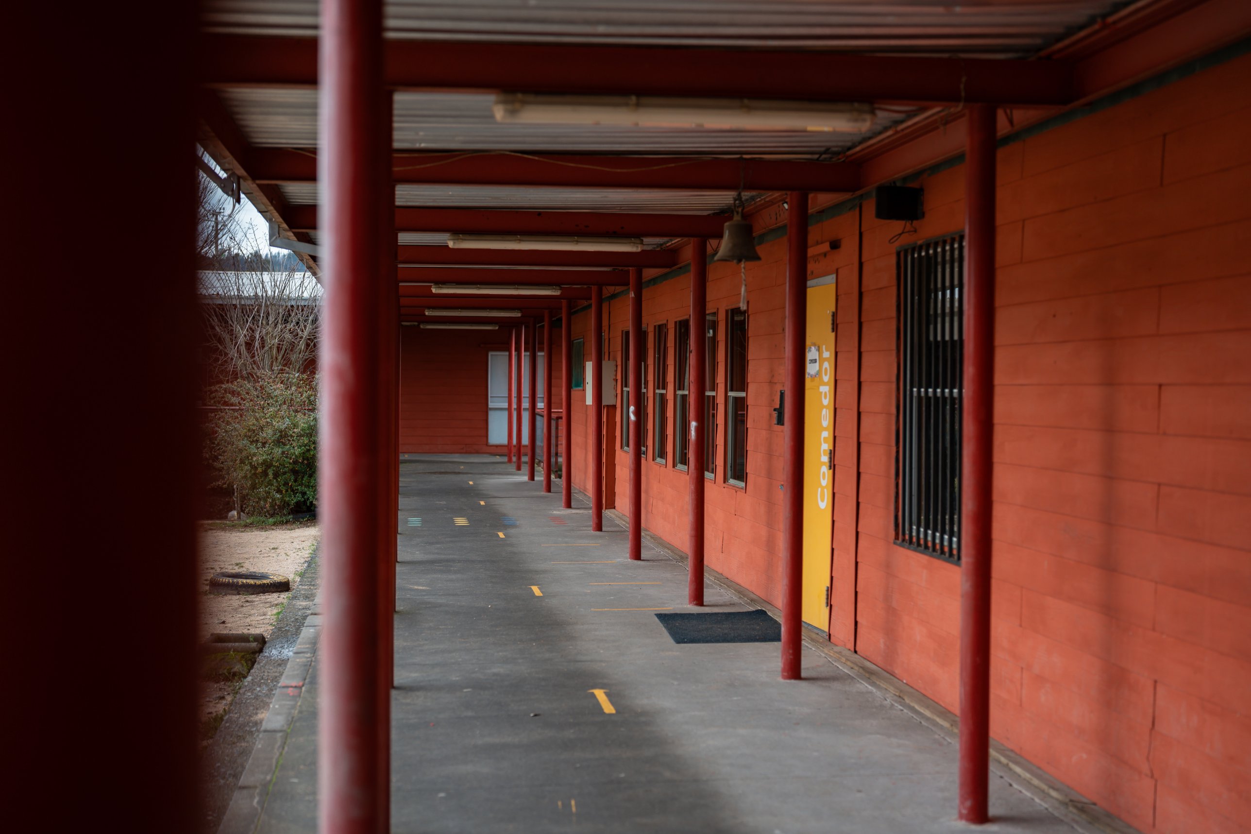 Pasillo techado de una escuela con la puerta del comedor